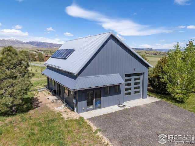 view of front of property featuring a garage, a mountain view, and solar panels