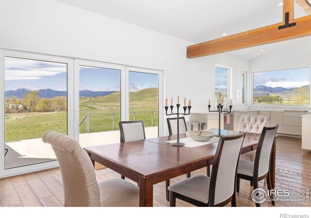 dining area featuring a mountain view, vaulted ceiling with beams, and light wood-type flooring