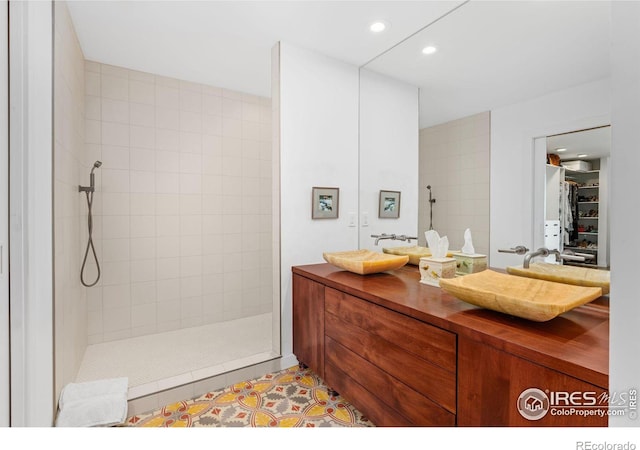 bathroom featuring vanity, tile patterned flooring, and a tile shower