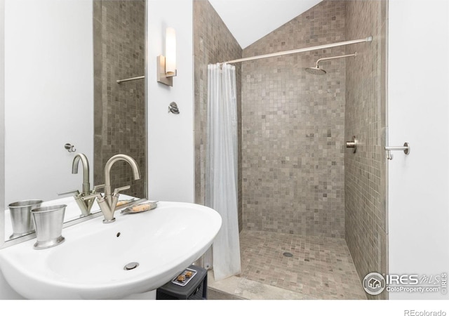 bathroom featuring vaulted ceiling, sink, and curtained shower