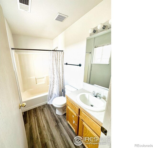 full bathroom with hardwood / wood-style flooring, shower / bath combination with curtain, toilet, and vanity