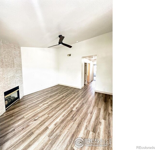 unfurnished living room featuring ceiling fan, a fireplace, a textured ceiling, and hardwood / wood-style flooring