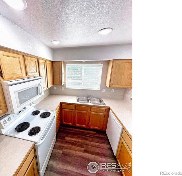 kitchen with dark wood-type flooring, white appliances, sink, and a textured ceiling