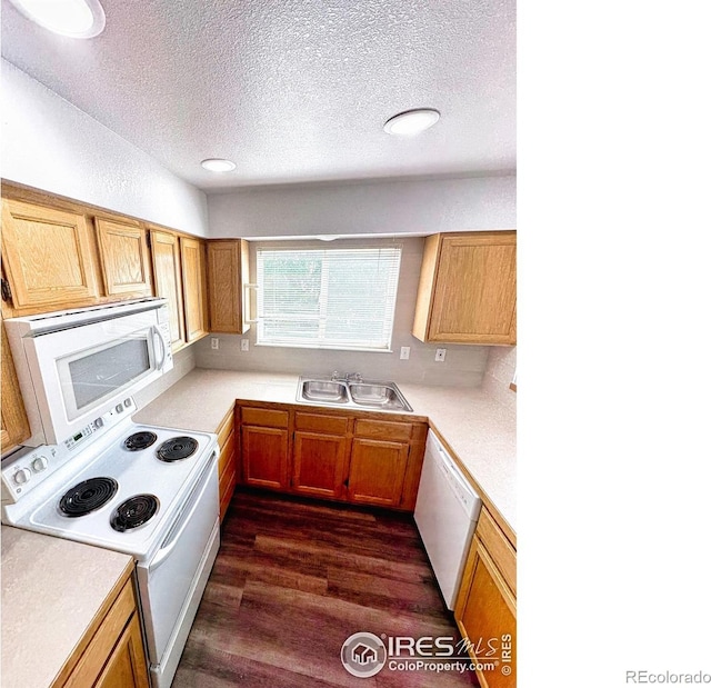 kitchen featuring a textured ceiling, white appliances, dark wood-style flooring, a sink, and light countertops