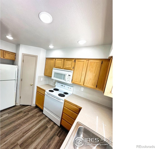 kitchen with light countertops, decorative backsplash, dark wood-type flooring, a textured ceiling, and white appliances