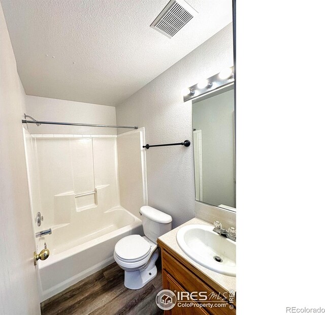 full bathroom with vanity, hardwood / wood-style floors, toilet, a textured ceiling, and bathtub / shower combination