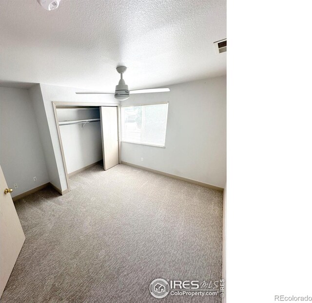 unfurnished bedroom featuring a closet, carpet, a textured ceiling, and ceiling fan