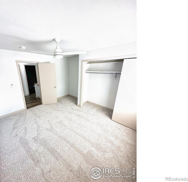 unfurnished bedroom featuring light carpet, a closet, a textured ceiling, and ceiling fan