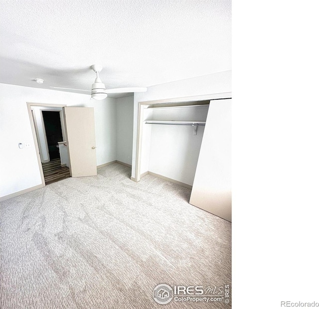 unfurnished bedroom featuring carpet, a closet, ceiling fan, a textured ceiling, and baseboards