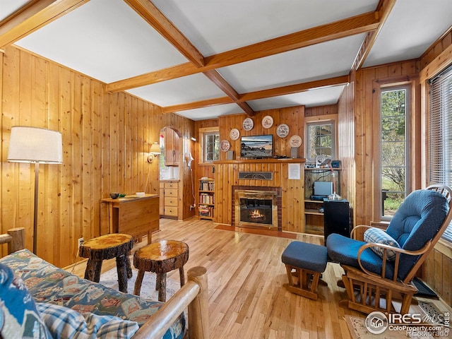 living room featuring beam ceiling, light wood-type flooring, and wood walls