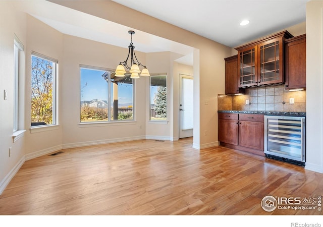 bar featuring light wood-type flooring, decorative light fixtures, tasteful backsplash, and wine cooler