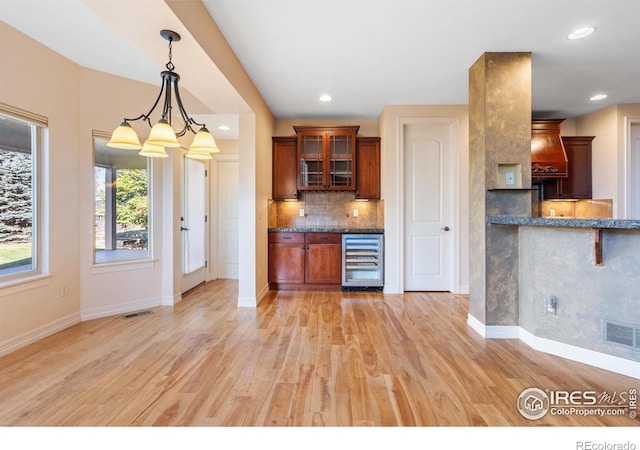 kitchen with wine cooler, light wood-type flooring, decorative light fixtures, and backsplash