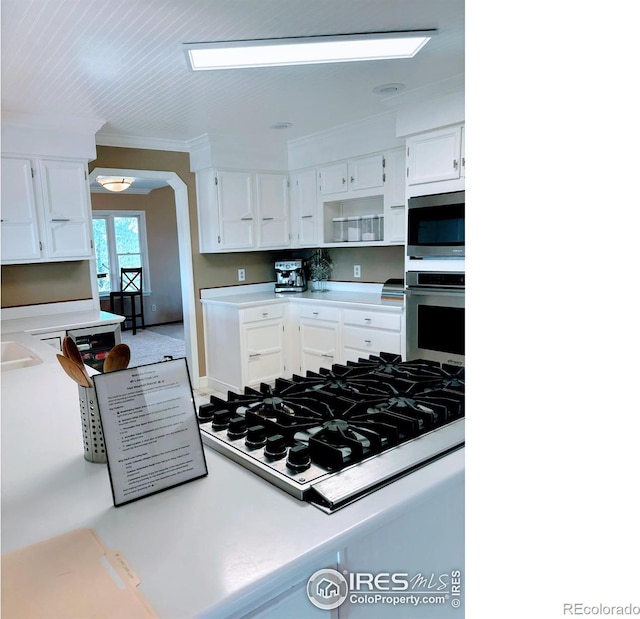 kitchen with white cabinets, light countertops, open shelves, and appliances with stainless steel finishes