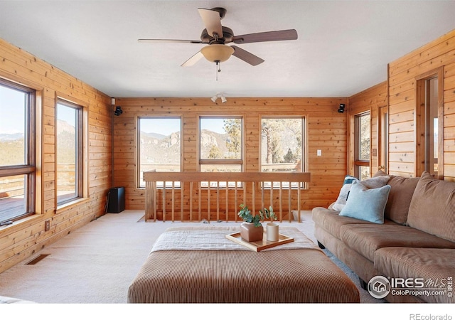 living room with light carpet, a wealth of natural light, and wooden walls