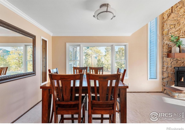 carpeted dining area featuring a fireplace, ornamental molding, a wood stove, and a healthy amount of sunlight