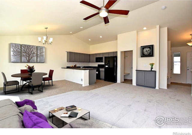 living room featuring light carpet, ceiling fan with notable chandelier, lofted ceiling, and sink