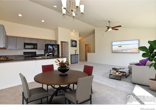 dining area with high vaulted ceiling and ceiling fan with notable chandelier