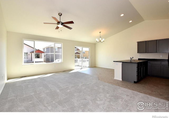 unfurnished living room with vaulted ceiling, light colored carpet, and ceiling fan with notable chandelier