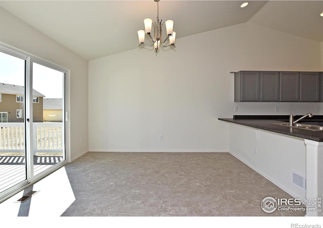 unfurnished dining area featuring vaulted ceiling, an inviting chandelier, a healthy amount of sunlight, and sink