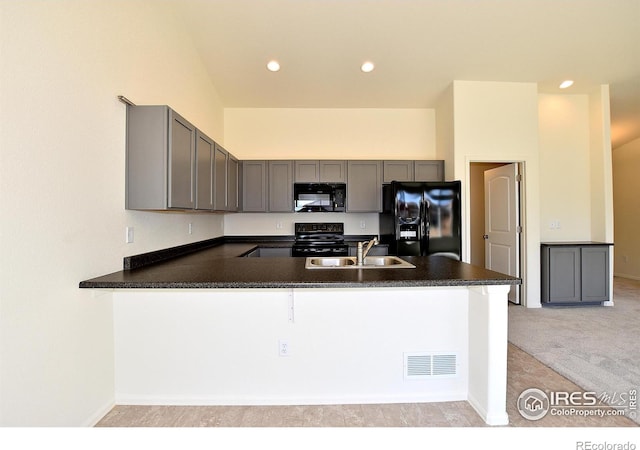 kitchen with black appliances, kitchen peninsula, sink, and light carpet