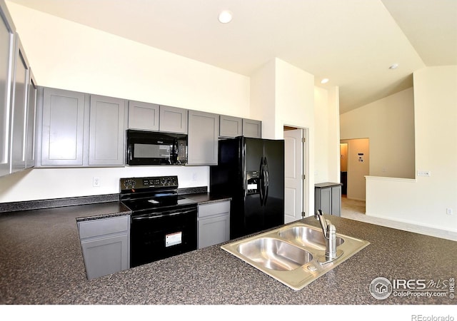 kitchen featuring sink, gray cabinets, lofted ceiling, and black appliances