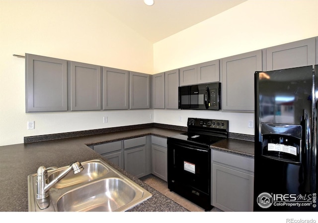 kitchen featuring gray cabinetry, sink, black appliances, and lofted ceiling