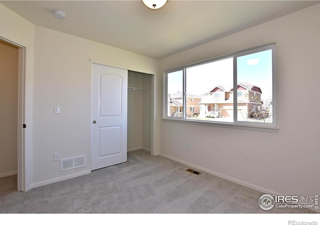 unfurnished bedroom featuring a closet and light colored carpet