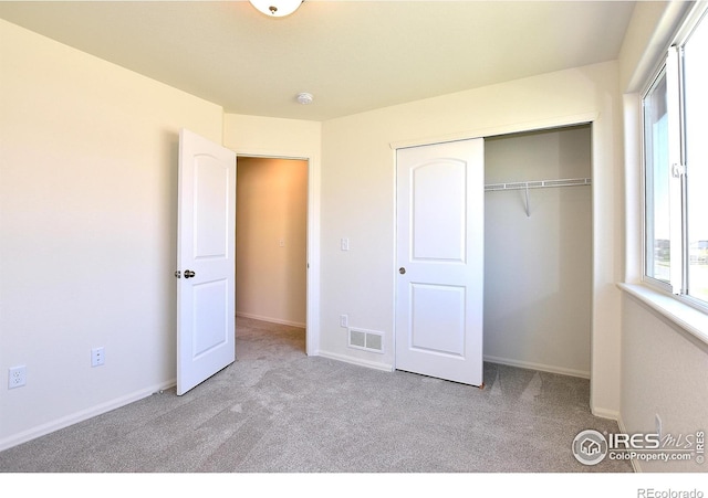 unfurnished bedroom with light carpet and a closet