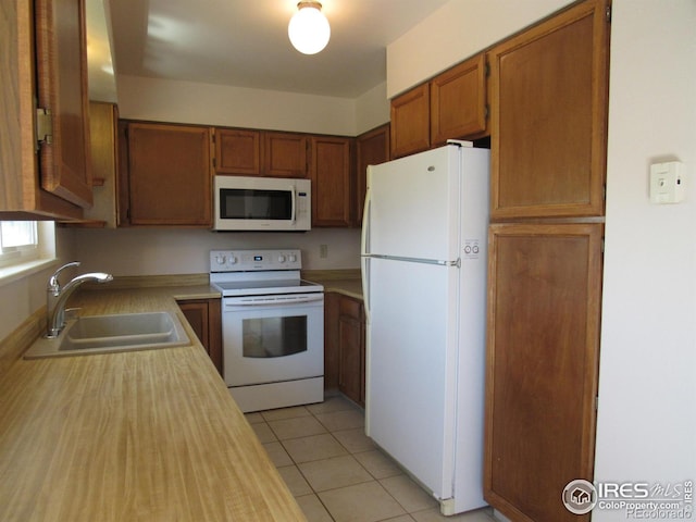 kitchen with sink, white appliances, and light tile flooring