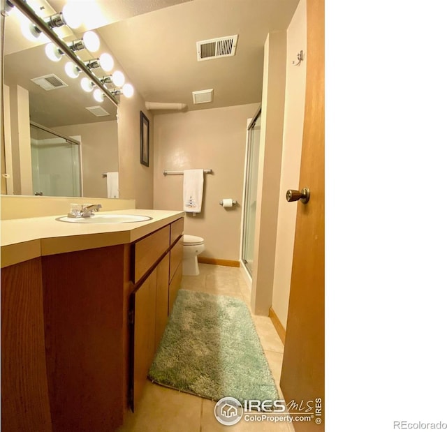 bathroom featuring tile patterned flooring, vanity, toilet, and walk in shower