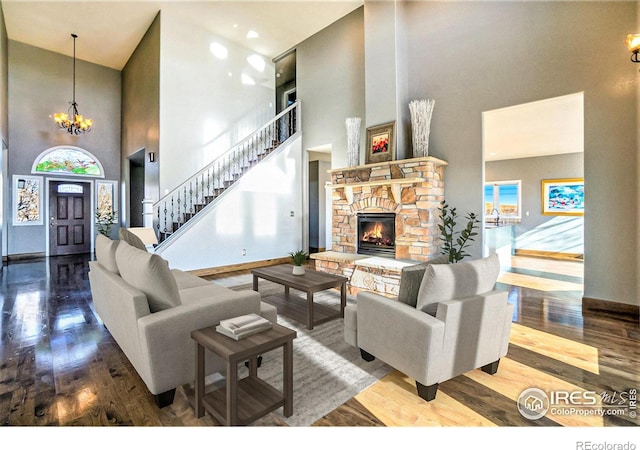 living room featuring hardwood / wood-style flooring, a fireplace, high vaulted ceiling, and an inviting chandelier