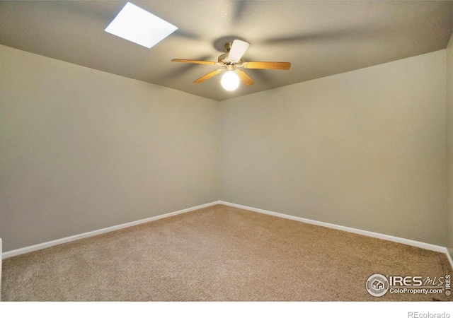 unfurnished room with a skylight, ceiling fan, and carpet