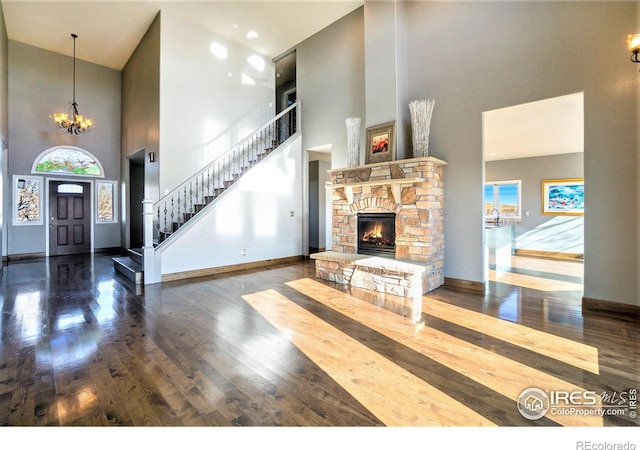 living room with a chandelier, a fireplace, a towering ceiling, and wood-type flooring