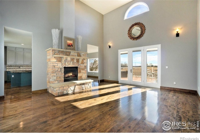 living room featuring a fireplace, dark wood-type flooring, and a high ceiling