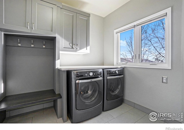 laundry room with washer and dryer, cabinets, and light tile patterned floors