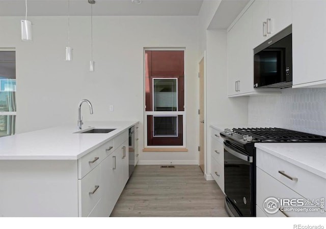 kitchen featuring white cabinets, gas stove, sink, light hardwood / wood-style floors, and decorative light fixtures