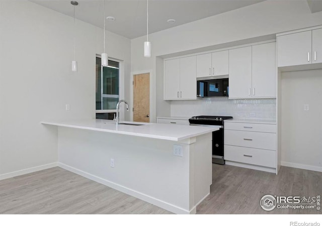 kitchen with light wood-type flooring, pendant lighting, sink, white cabinets, and appliances with stainless steel finishes