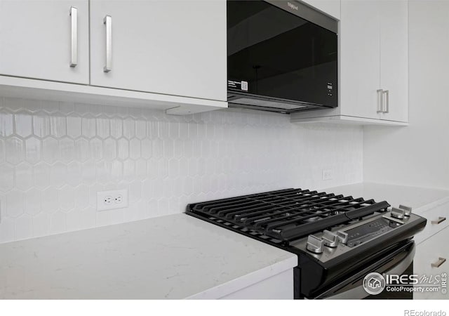 kitchen featuring light stone counters, black appliances, decorative backsplash, and white cabinetry