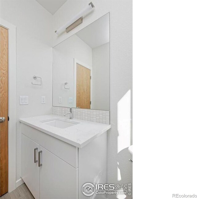 bathroom with hardwood / wood-style floors, decorative backsplash, and vanity