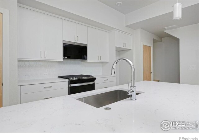 kitchen featuring light stone counters, white cabinets, hanging light fixtures, sink, and stainless steel appliances