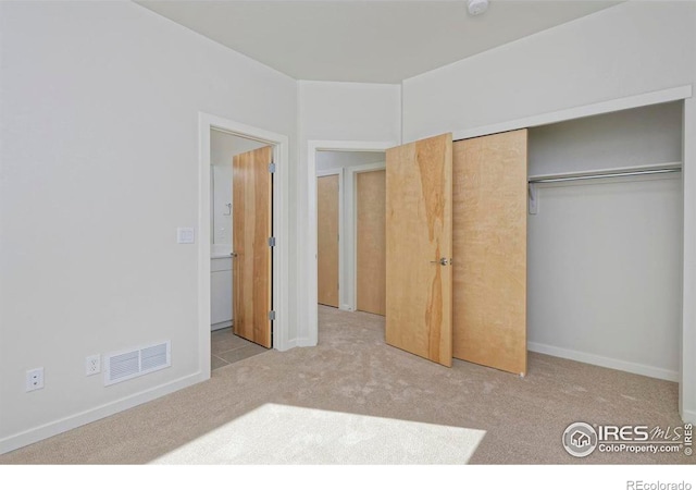 unfurnished bedroom with a closet and light colored carpet