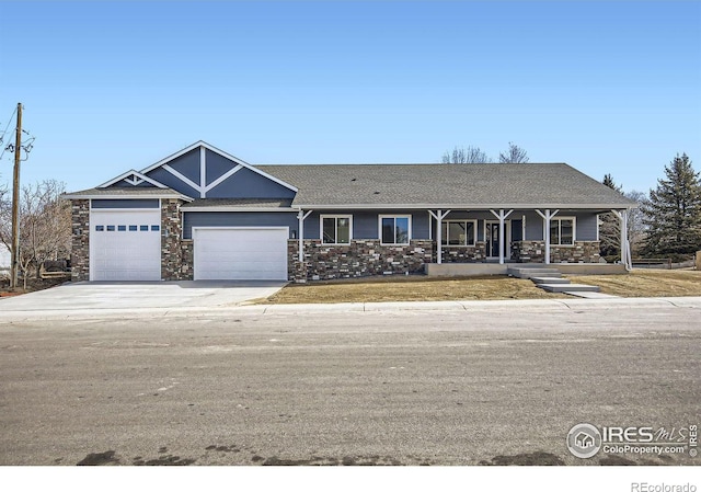 view of front of property featuring an attached garage, stone siding, and concrete driveway