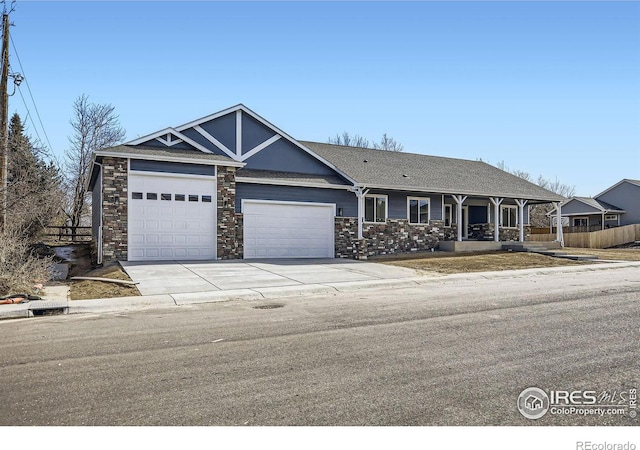 view of front of house with a garage, concrete driveway, stone siding, and fence