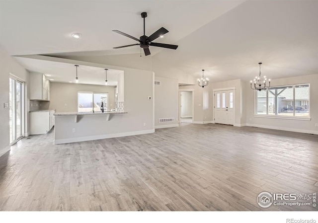 unfurnished living room featuring baseboards, visible vents, vaulted ceiling, light wood-style floors, and ceiling fan with notable chandelier