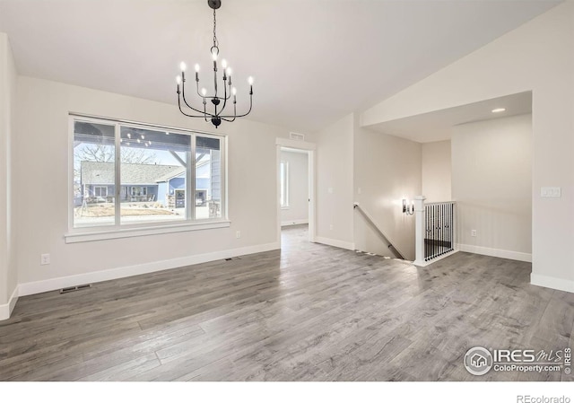 unfurnished dining area featuring baseboards, wood finished floors, lofted ceiling, and a notable chandelier