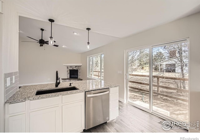 kitchen featuring dishwasher, decorative light fixtures, light stone countertops, white cabinetry, and a sink