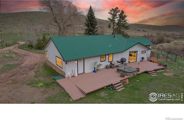 back house at dusk featuring a wooden deck