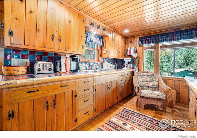 kitchen with sink, wood walls, and light wood-type flooring