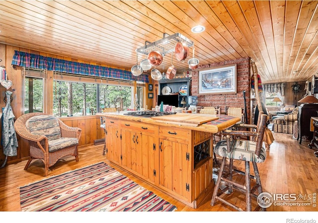 kitchen featuring brick wall, wooden ceiling, wooden walls, and light hardwood / wood-style flooring