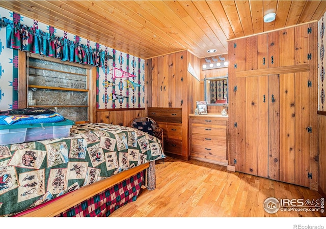 bedroom with light hardwood / wood-style flooring, wood walls, and wooden ceiling